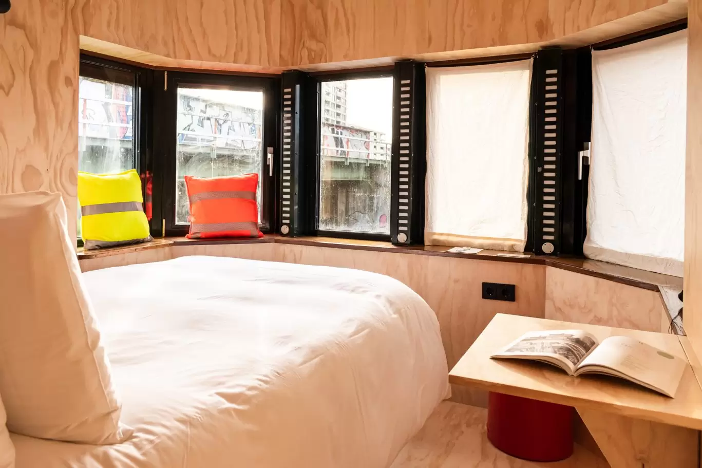 Bed, seating area and windows of SWEETS hotel's bridge house Omvalbrug