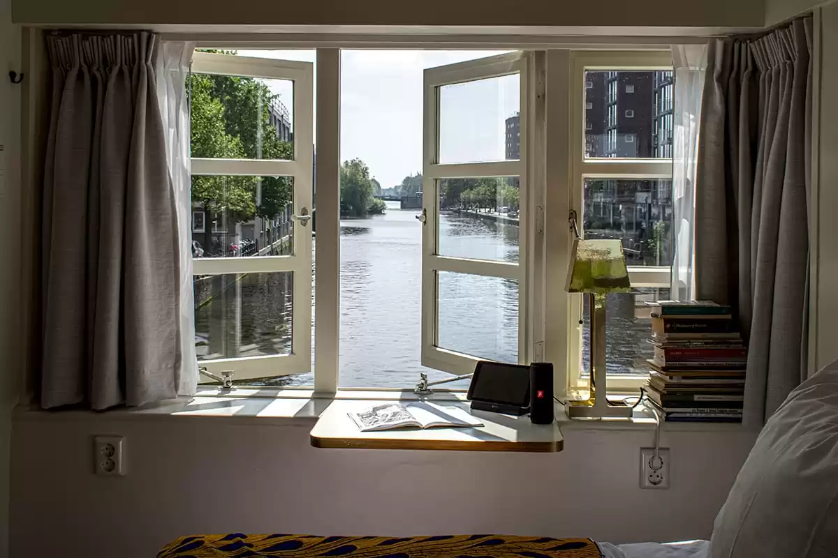 Photo of SWEETS hotel Amsterdam West Van Hallbrug bridge house interior hotel near Amsterdam Center view from bedroom living space water view books